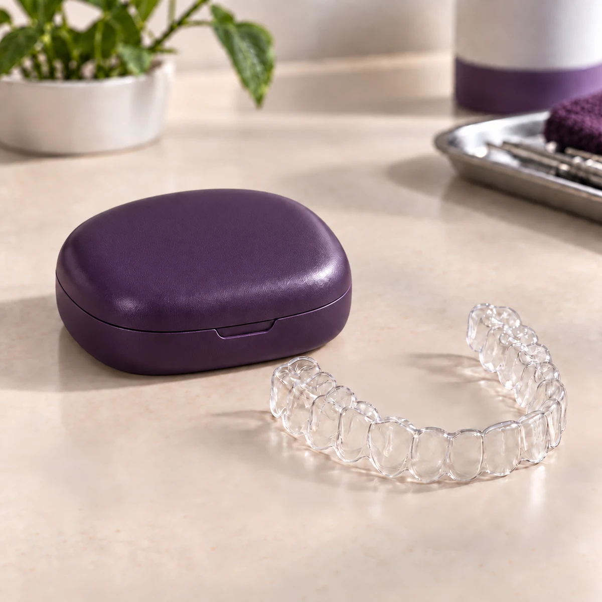 Clear aligner beside a plum-colored storage case